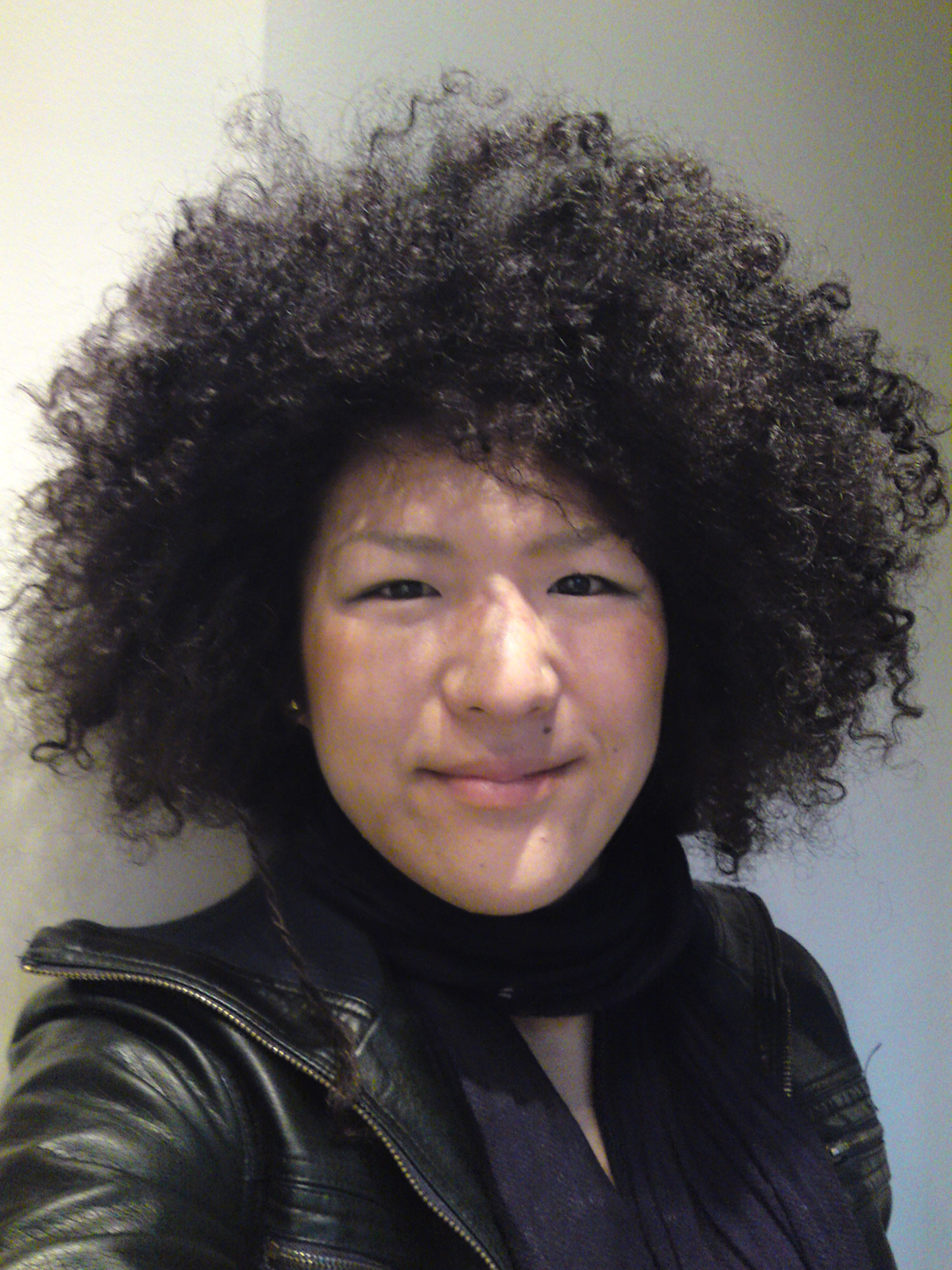 A selfie taken by a woman of East Asian descent with big hair wearing a black scarf and leather jacket.