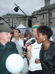 A black woman speaks into a microphone and looks towards the audience