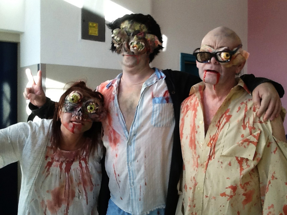 Artistic Director Maria Oshodi shares a team hug with two fellow Zombies in full make up and bloodied costumes