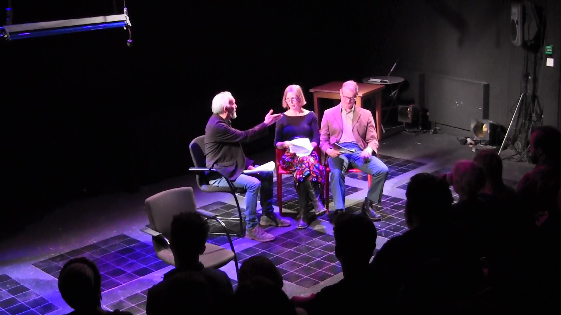 Actor Christopher facing actors Heather and Miles sat on a row of chairs facing the audience.