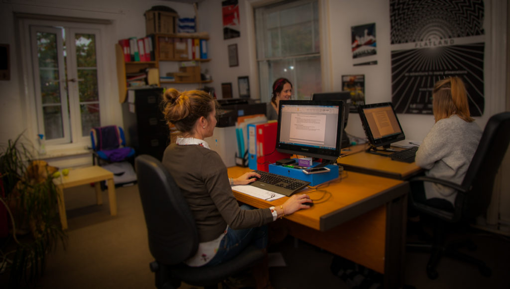 Three female team members sat working at desks in the Extant office