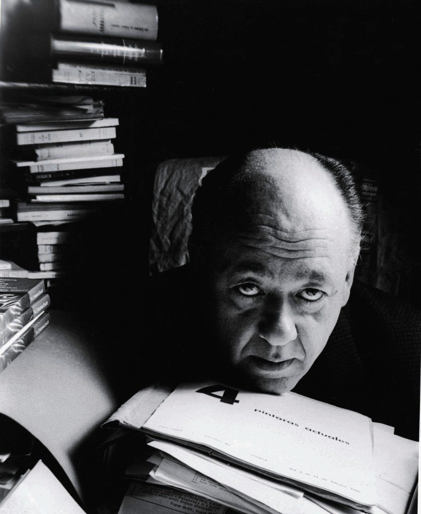 Absurd dramatist Eugene Ionesco rests his head on a pile of manuscript and journals