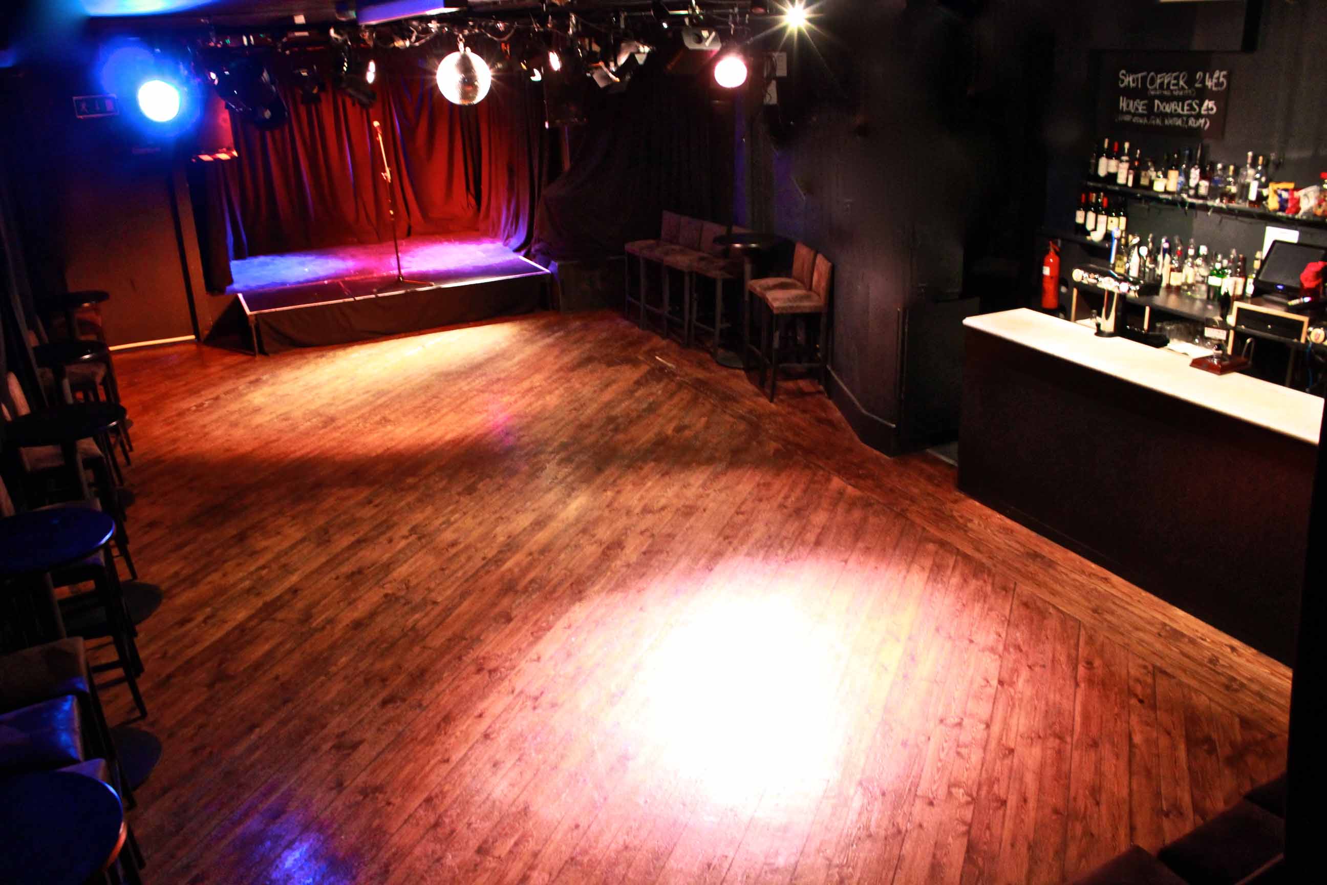 (from above) interior of the Komedia studio, without seating. stage lit up in red and purple