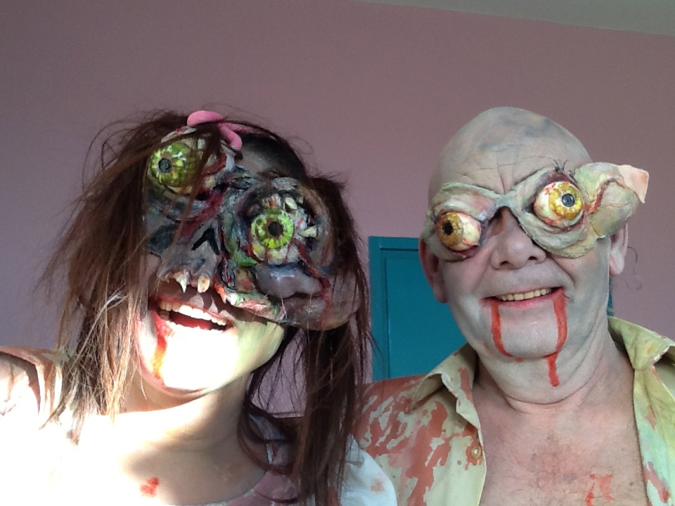 Zombies Maria and Stripe grin incongruously at camera wearing horrific prosthetic Zombie eyes and bloody makeup