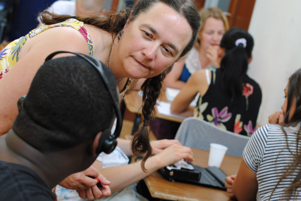Writer Louise Jenkins leans over to talk to a participant who is wearing headphones
