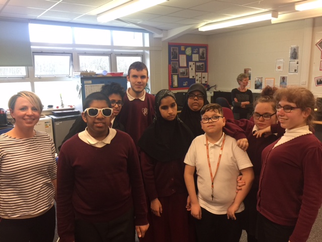 students from the project huddled together in a classroom, smiling at the camera