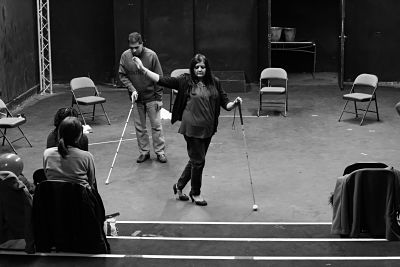 Participants demonstrate movement work with white canes in front of a small audience