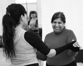 A female dance teacher holds the hands of a smiling dance participant. Black and white image