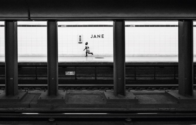Black and white shot of a young girl running along a deserted station platform