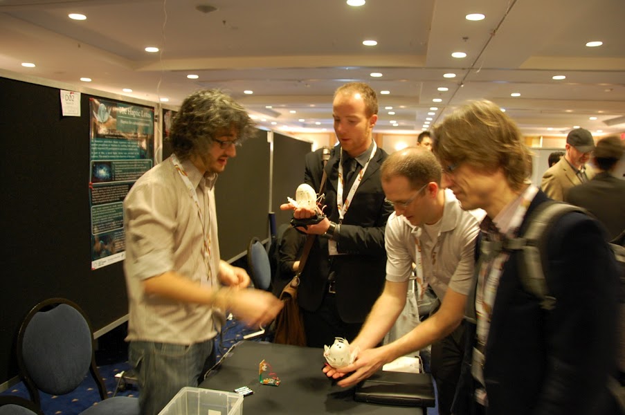 robotics specialist Adam Spiers shows the haptic lotus to visitors at his stand at the symposium. The visitors are holding the lotuses