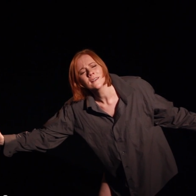 Maggie Tolmie arms outstretched during a monologue