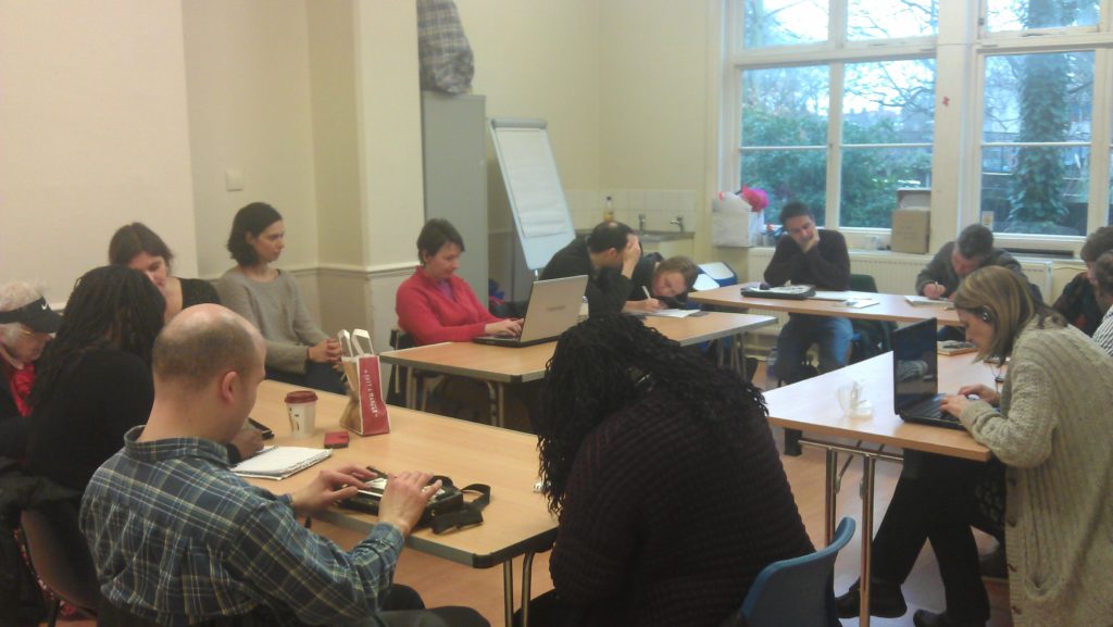 A room of writers working around a table on their scripts