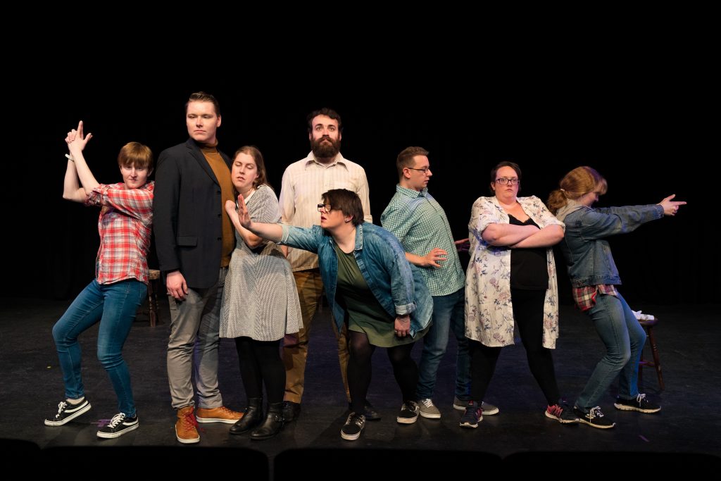 The pathways actors stand together in a line, they stand in an array of poses, arms folded, reaching out, hands on hips and pointing guns fashioned from their hands.
