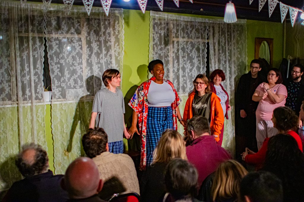 A young white man and black woman face the audience, shoulders tense as  if in preparation of something