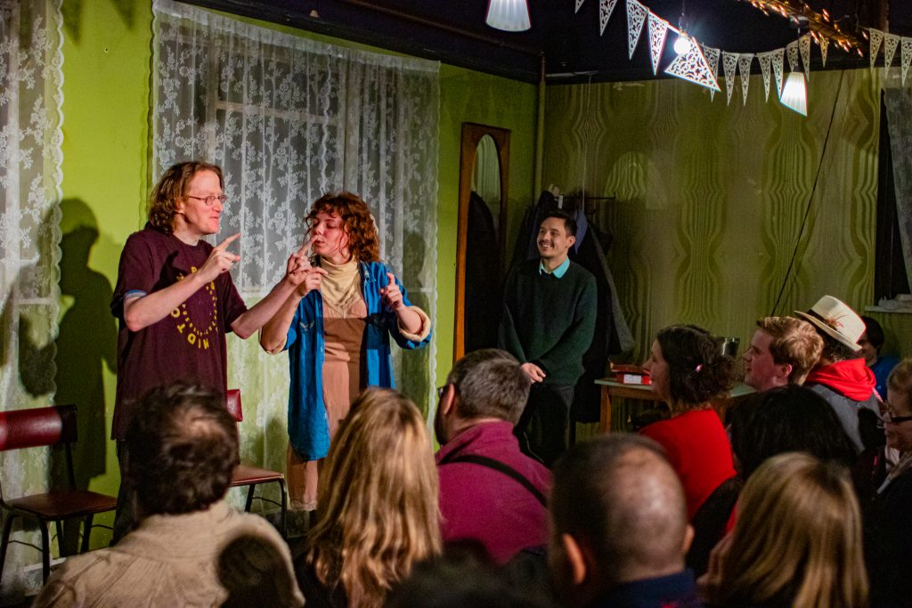 An older white man and a young woman on stage with both their hands pointing up