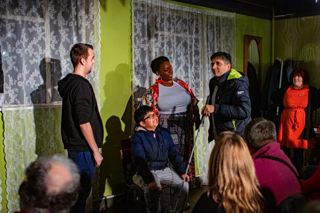 Four people on stage in conversation - a white man, a young boy sitting down, a black woman and a man holding a cane