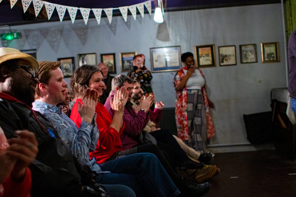 SIde view of the front row of the audience smiling and clapping