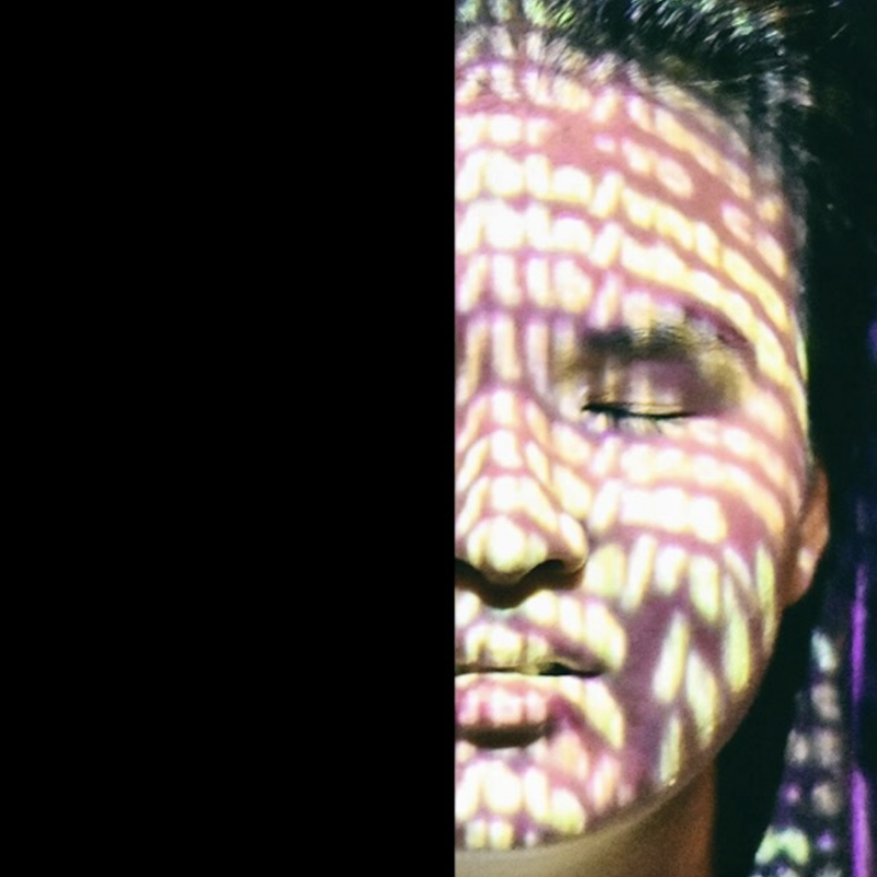 A photo image of the right half of a young Chinese woman's face. Her eye is closed. Bright light dapples across her skin.