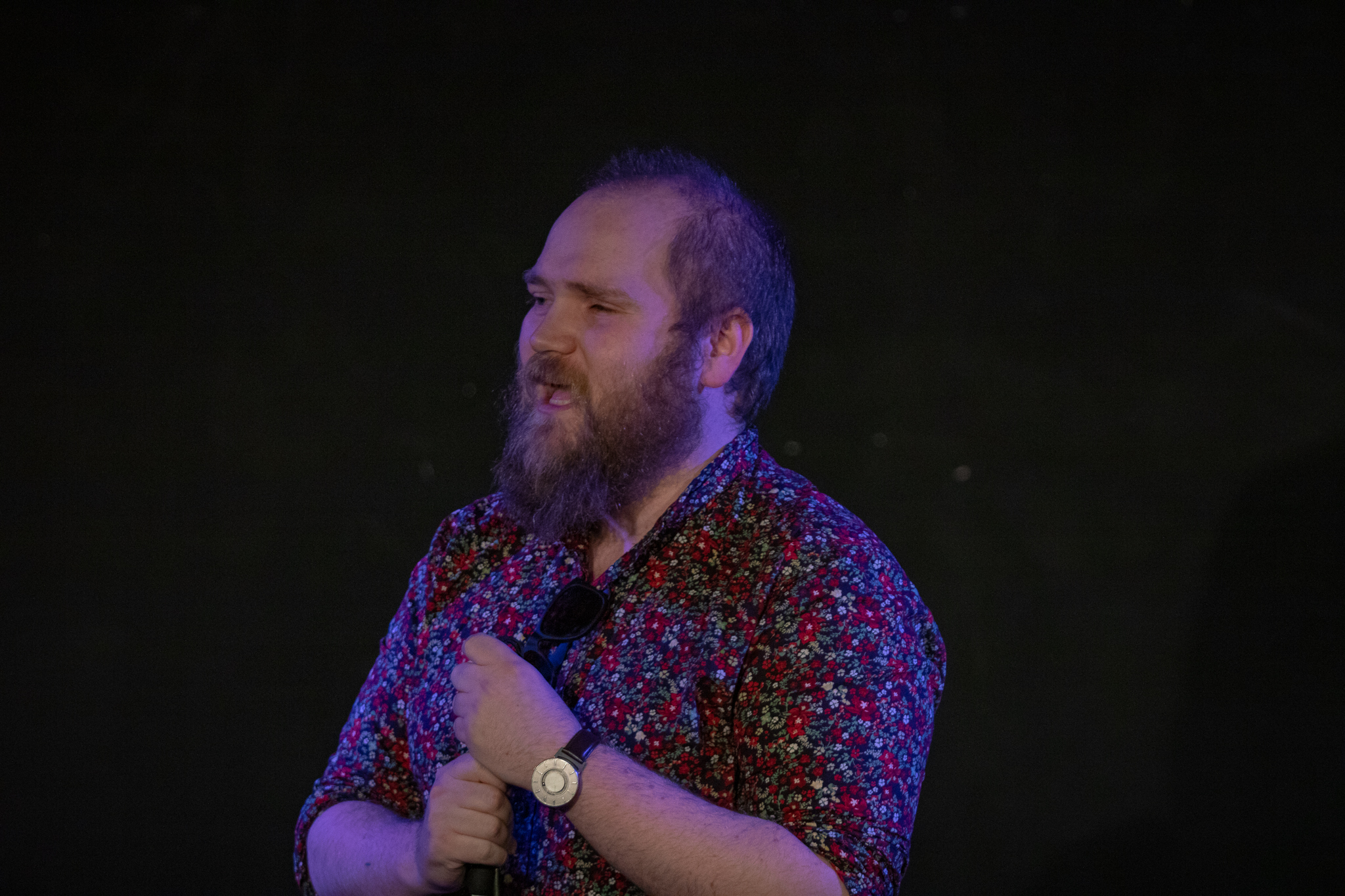 Ben Wilson, a white man, with short blonde hair and a beard. He wears a floral shirt and is talking mid-sentence.