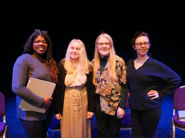 A group of four female panellists stand on a stage. 