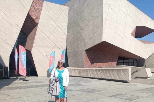 Maria standing in front of CKK Jordanki cultural centre with unusual architecture smiling in sun.
