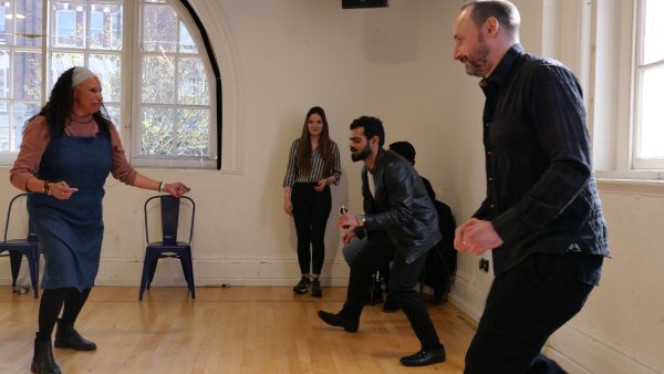 Maria has her feet planted on the floor and faces Shashank and Chris who are crouching.
